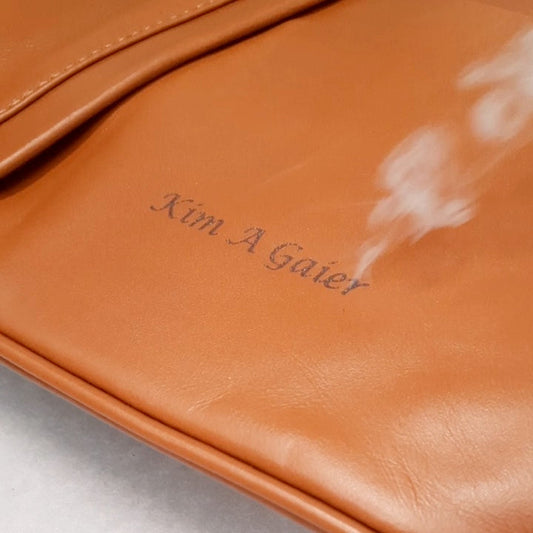 Laser engraving a name onto a caramel brown Italian leather handbag at the Tuscany Leather factory