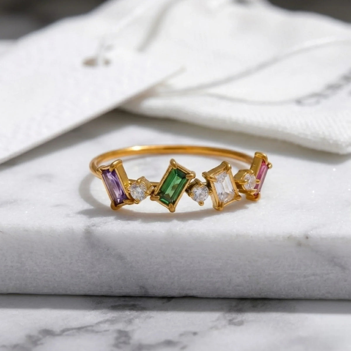 Anello dorato con gemme colorate su una superficie in marmo
