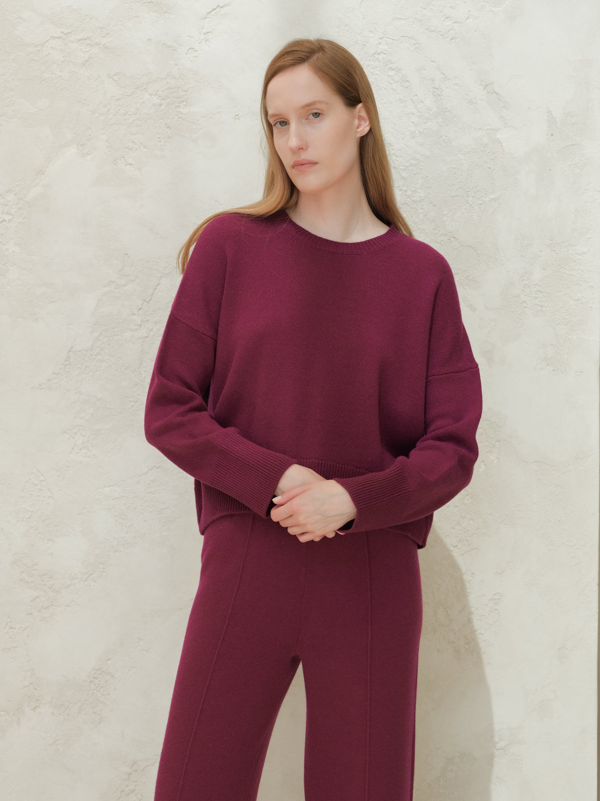 Mannequin portant a deep burgundy cashmere mix pull col rond with matching knit pants against a textured light wall