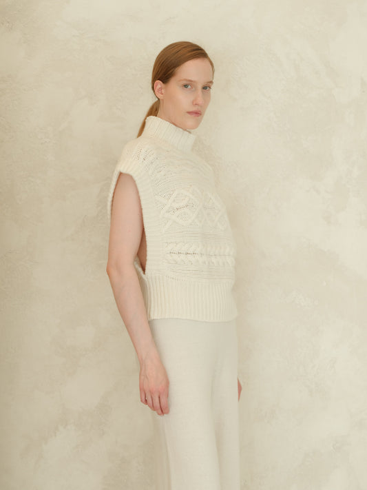 Model in ivory cashmere mix maxi cable tunic featuring a high neck and bold cable patterns.