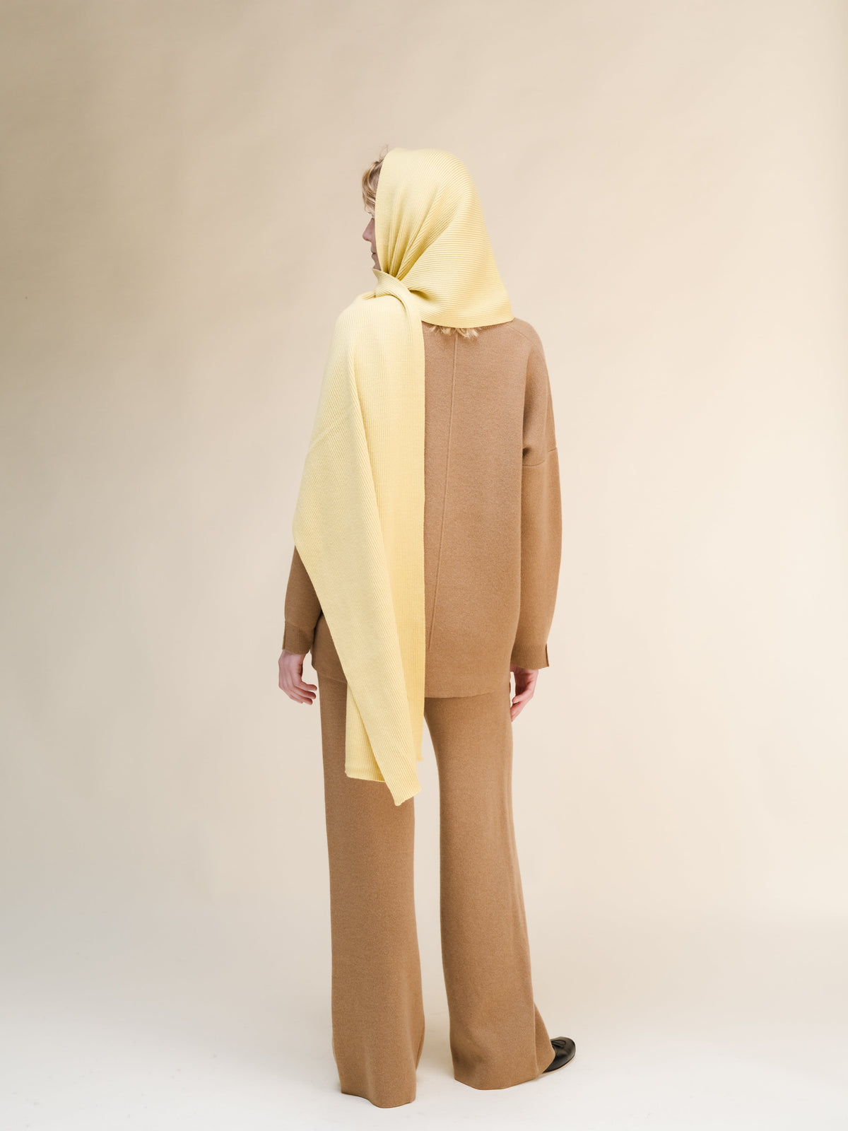 Person wearing a beige hijab and brown outfit on a plain background