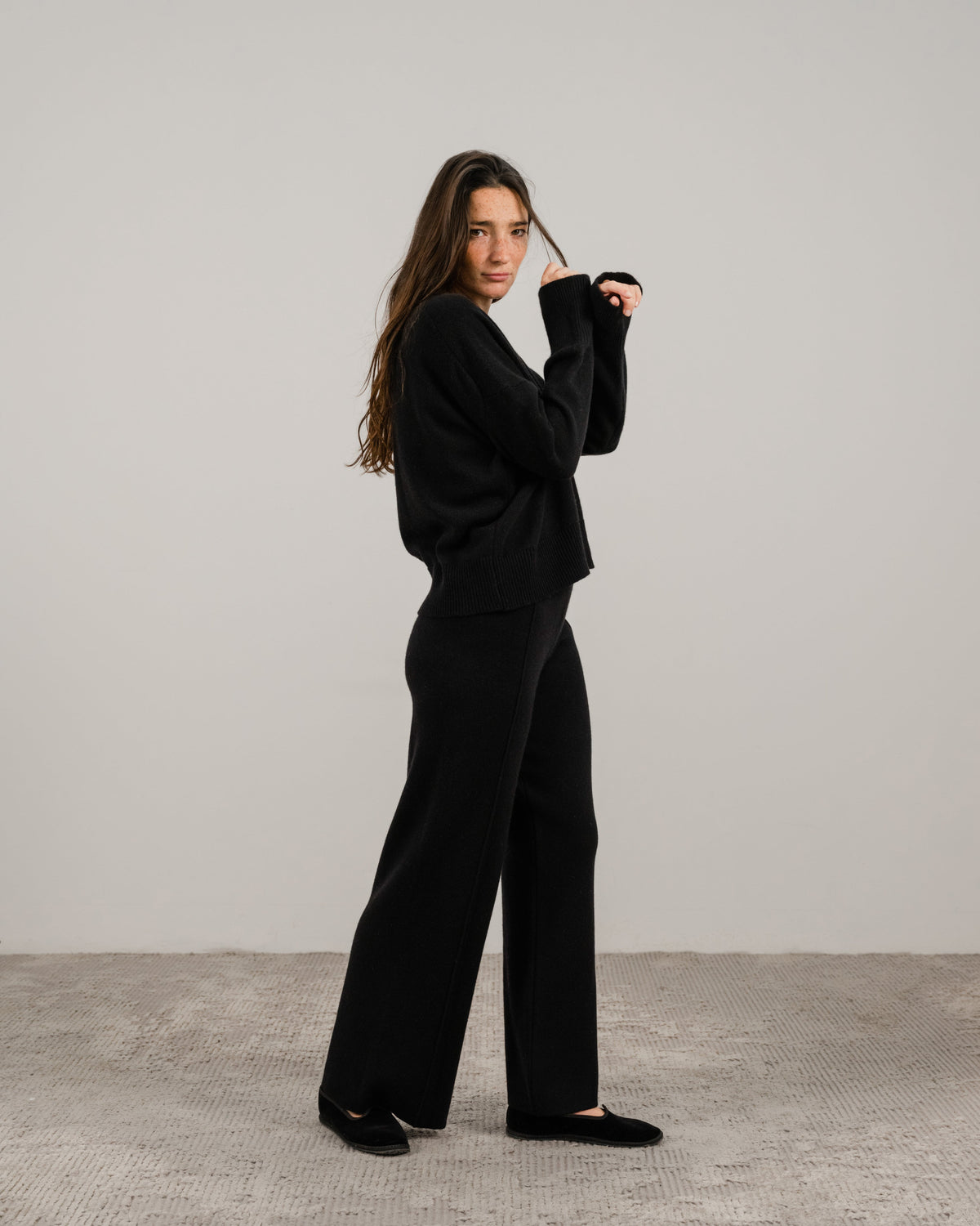 Full body vue de côté of a woman in a black cashmere mix pull col rond with pantalon large