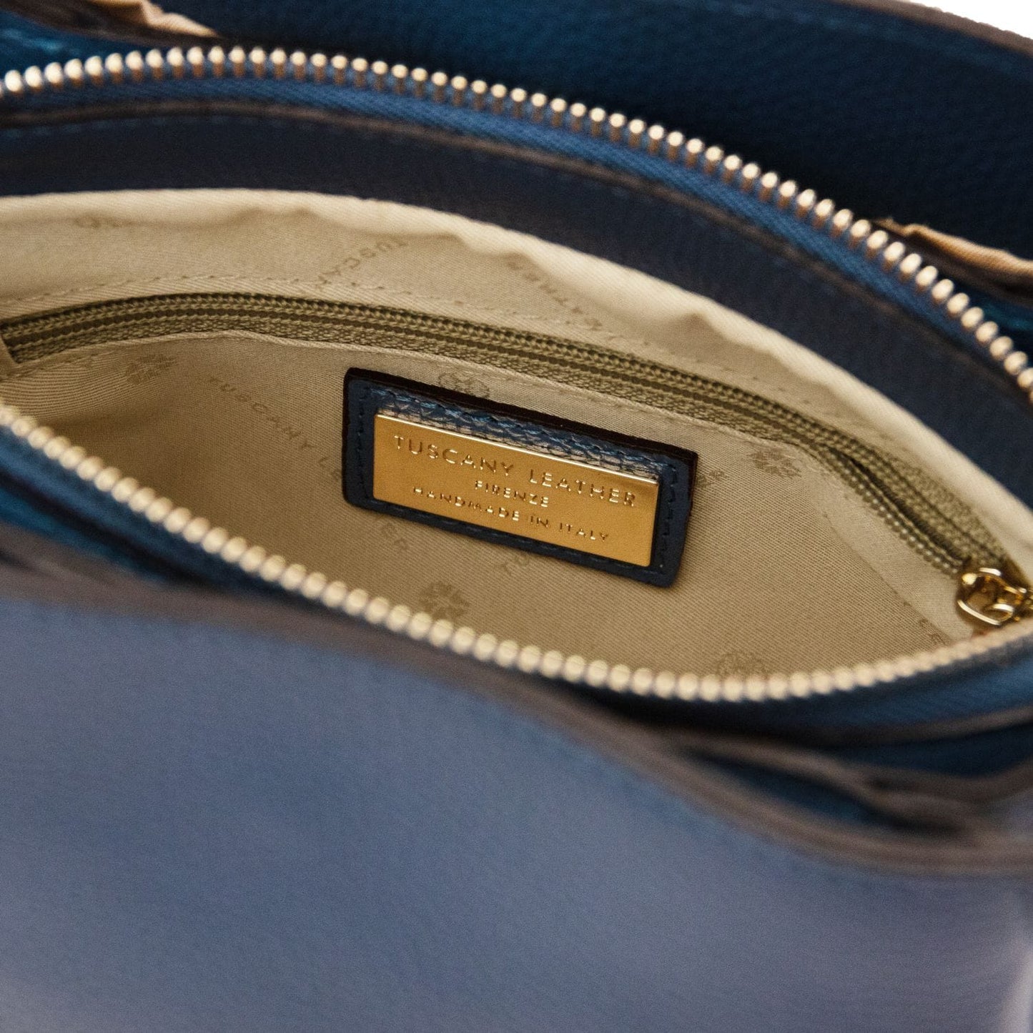 Interior of Abby leather shoulder bag with beige lining and gold label plaque
