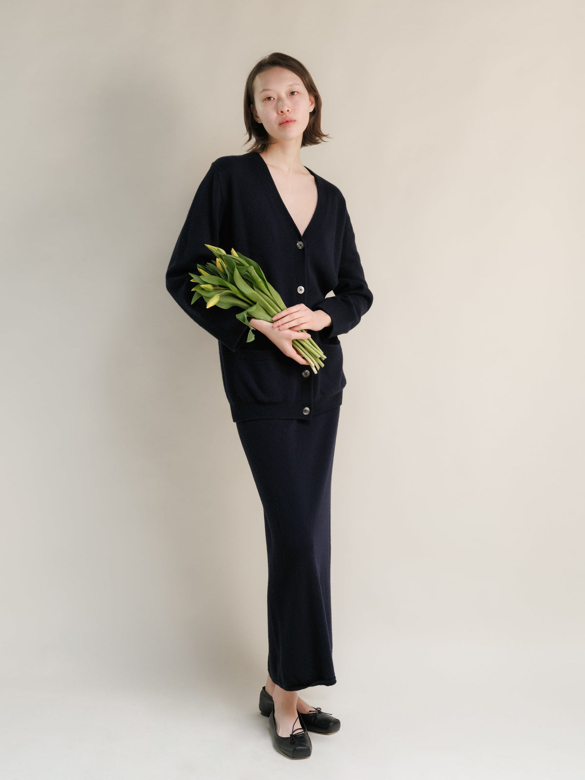Model in marineblau Cardigan aus Kaschmirmischung and coordinating langer Rock, mit einem Blumenstrauss