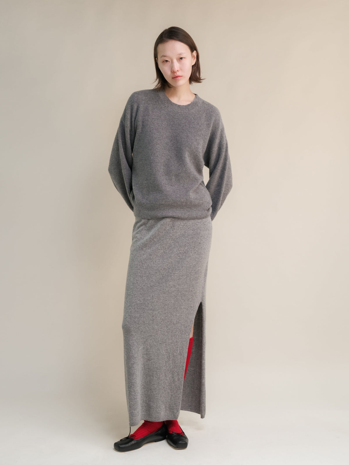 Model trägt gray cashmere blend high-waist langer Rock with a Seitenschlitz and a passendes Strickoberteil