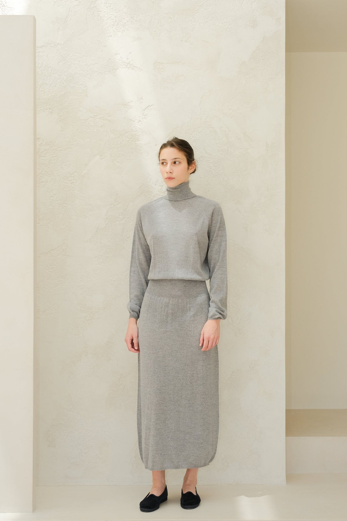 Model in grey coltrui and matching knit skirt from the jurk van extra fijne merinowol collection.