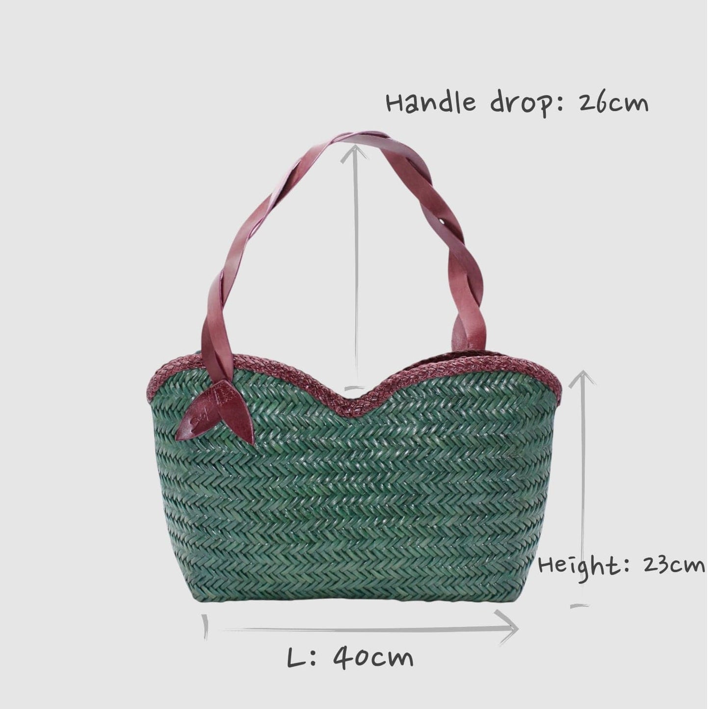 Green handwoven leather shoulder bag with pink ribbon handles and burgundy trim