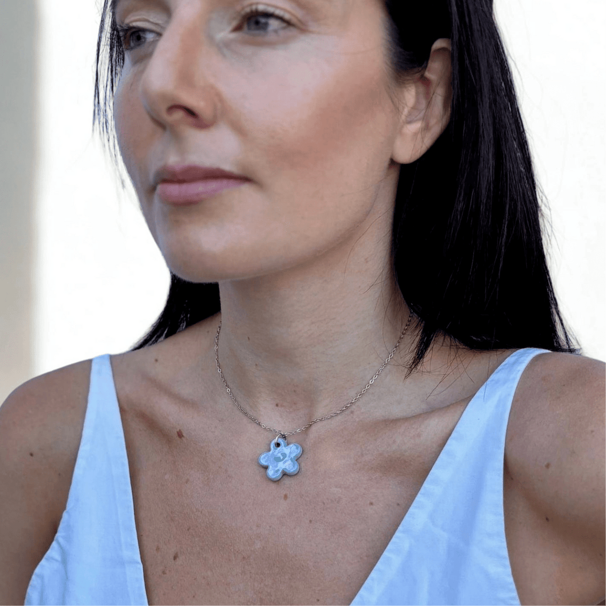 Lillium light blue floral ceramic necklace worn by a model with the pendant resting at the collarbone