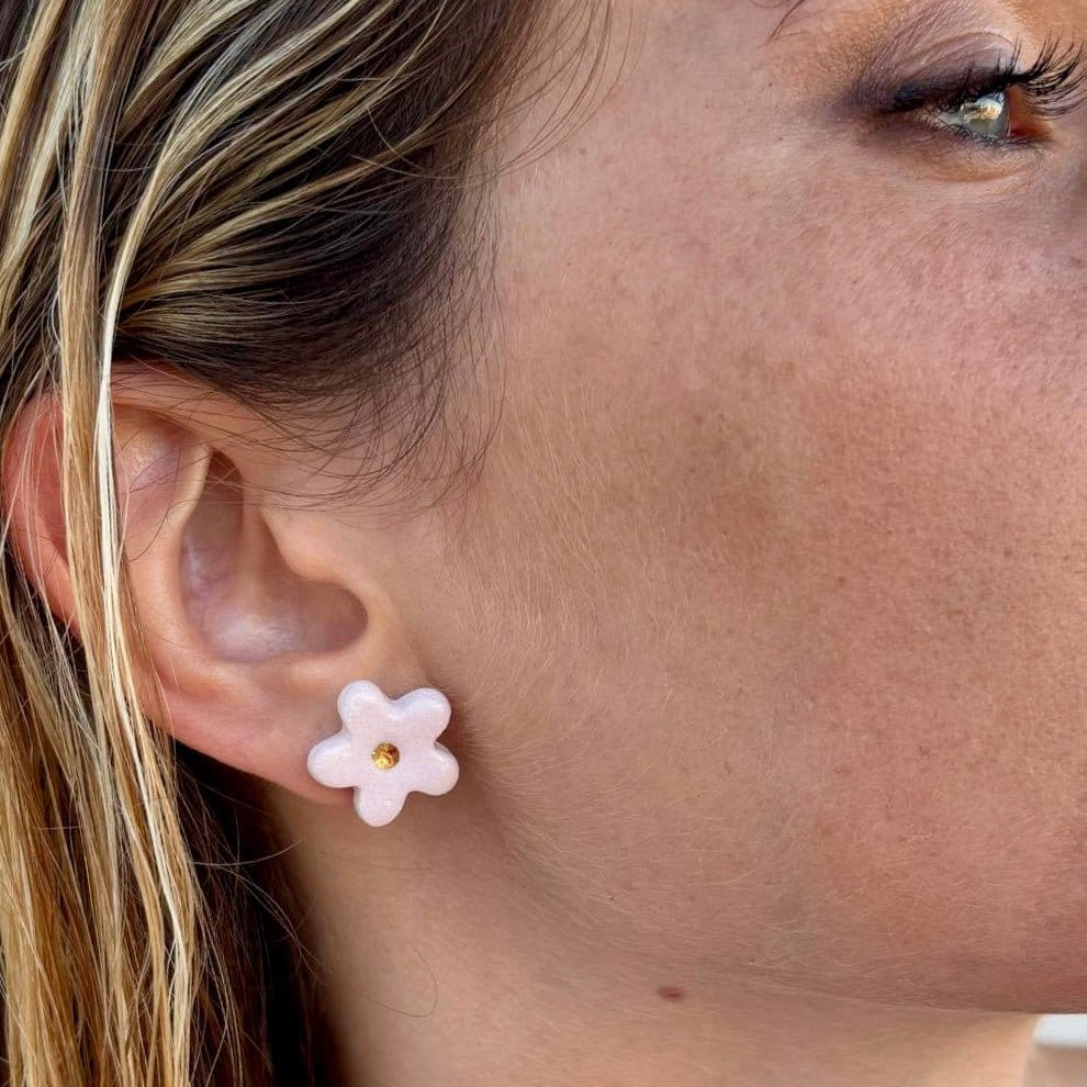Pink floral ceramic stud earring with gold center worn on the ear