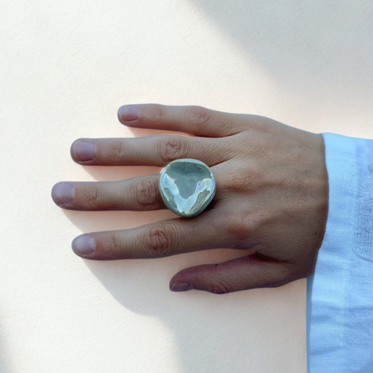 Round sage green ceramic ring worn on a finger