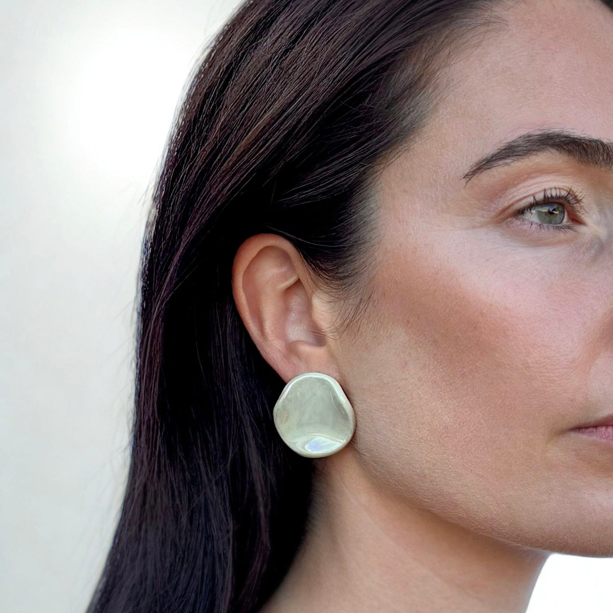 Clou d’oreille en céramique vert sauge de forme organique arrondie porté par un mannequin