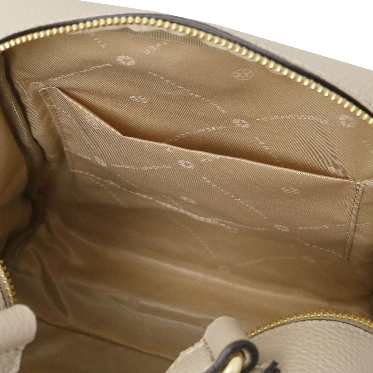 Open tan leather backpack interior with a zip pocket and light beige lining.