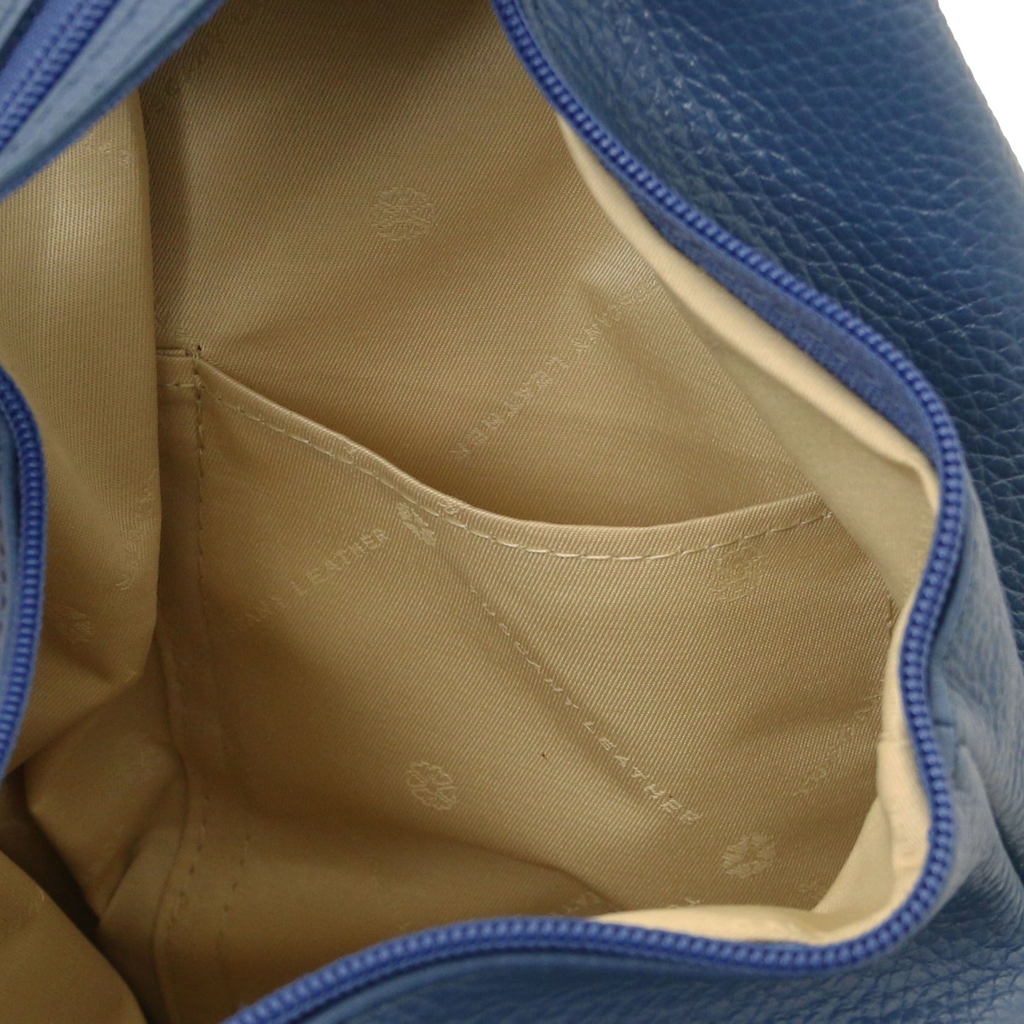 Close up of the interior pocket area of the blue backpack with beige lining.