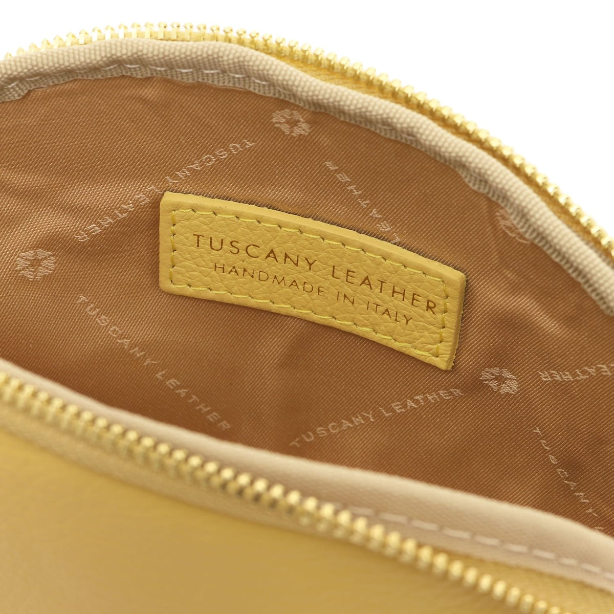 Gros plan of cuir souple toiletry case interior showing doublure en tissu and stitched Tuscany Leather label inside zipper opening.