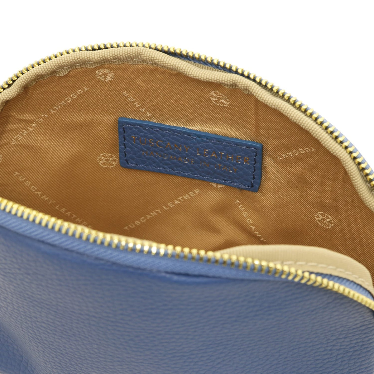 Gros plan of blue leather toiletry case interior showing beige doublure en tissu and embossed Tuscany Leather made in Italy label.
