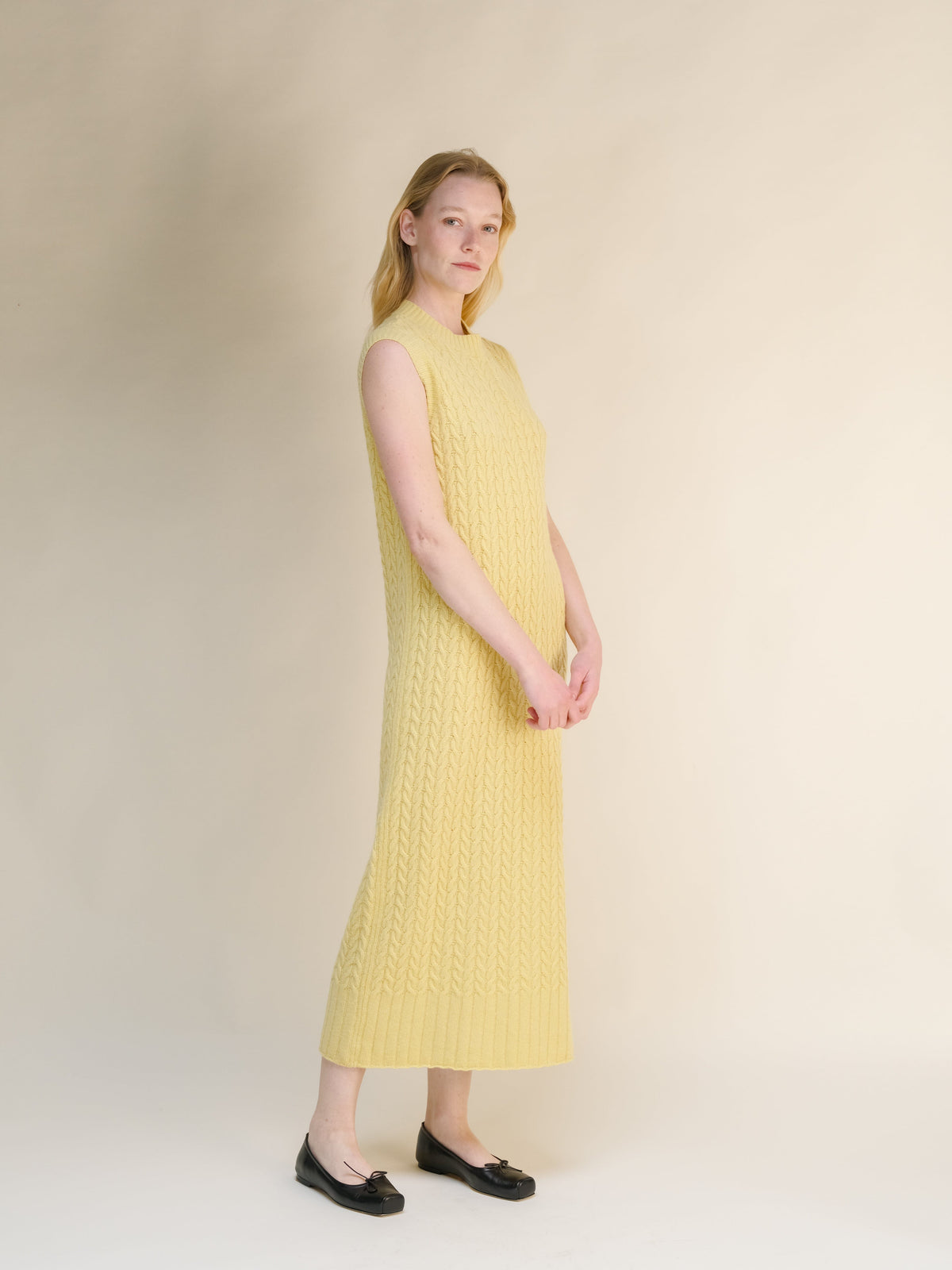 Wool & Cashmere Mix Sleeveless Cable Knit Dress in soft yellow with textured knit pattern and ribbed hem in a long midi length.
