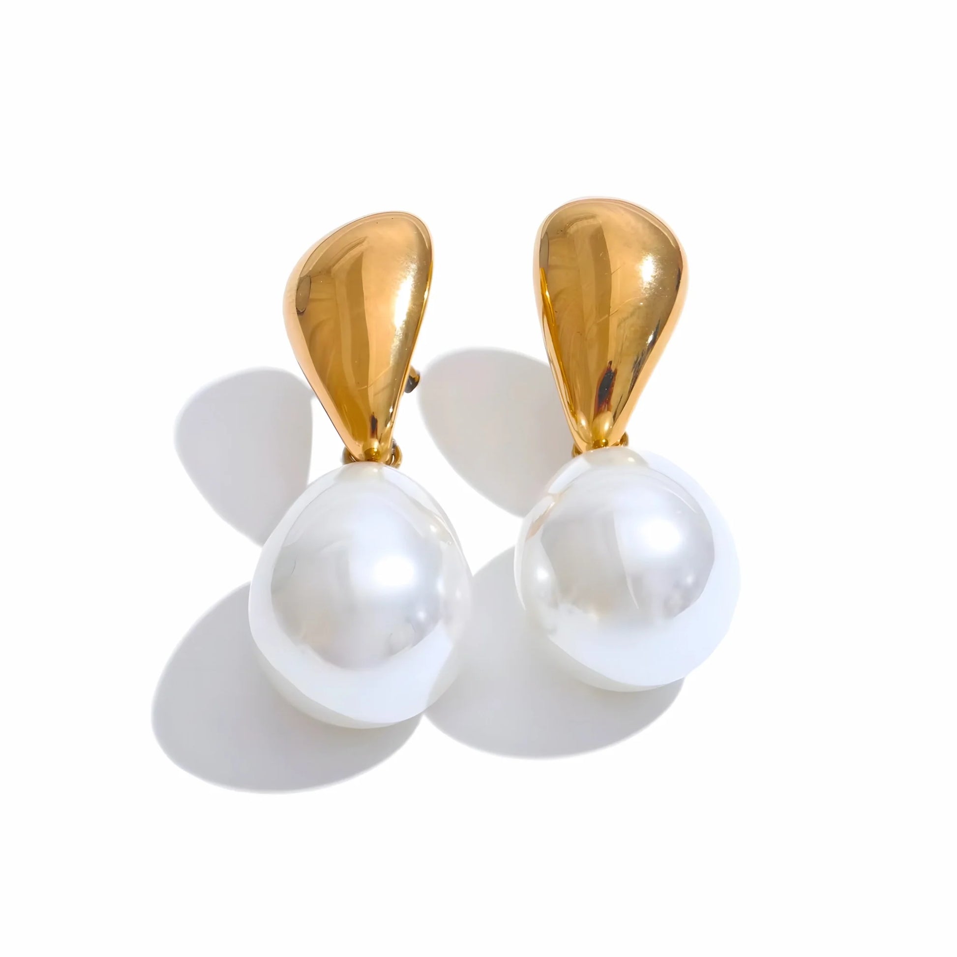 Pair of earrings with gold tops and white pearls on a white background