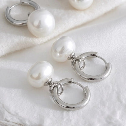 Silver hoop earrings with pearl beads on a white fabric background