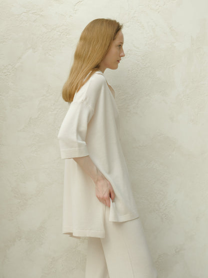 Side profile of a model wearing an oversized off white Extra Fine Merino Wool Maxi Polo with three quarter sleeves.
