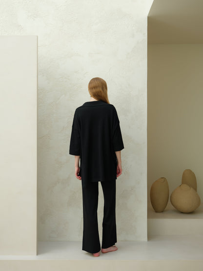 Back view of a model wearing a black Merino Wool Maxi Polo with an oversized silhouette
