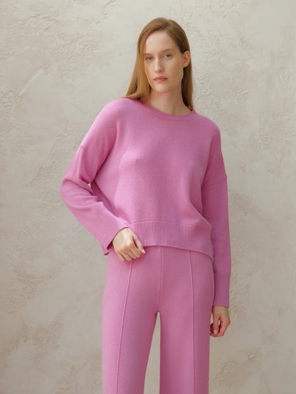 Model wearing pink cashmere mix crewneck sweater with matching pink knit pants against a neutral backdrop.