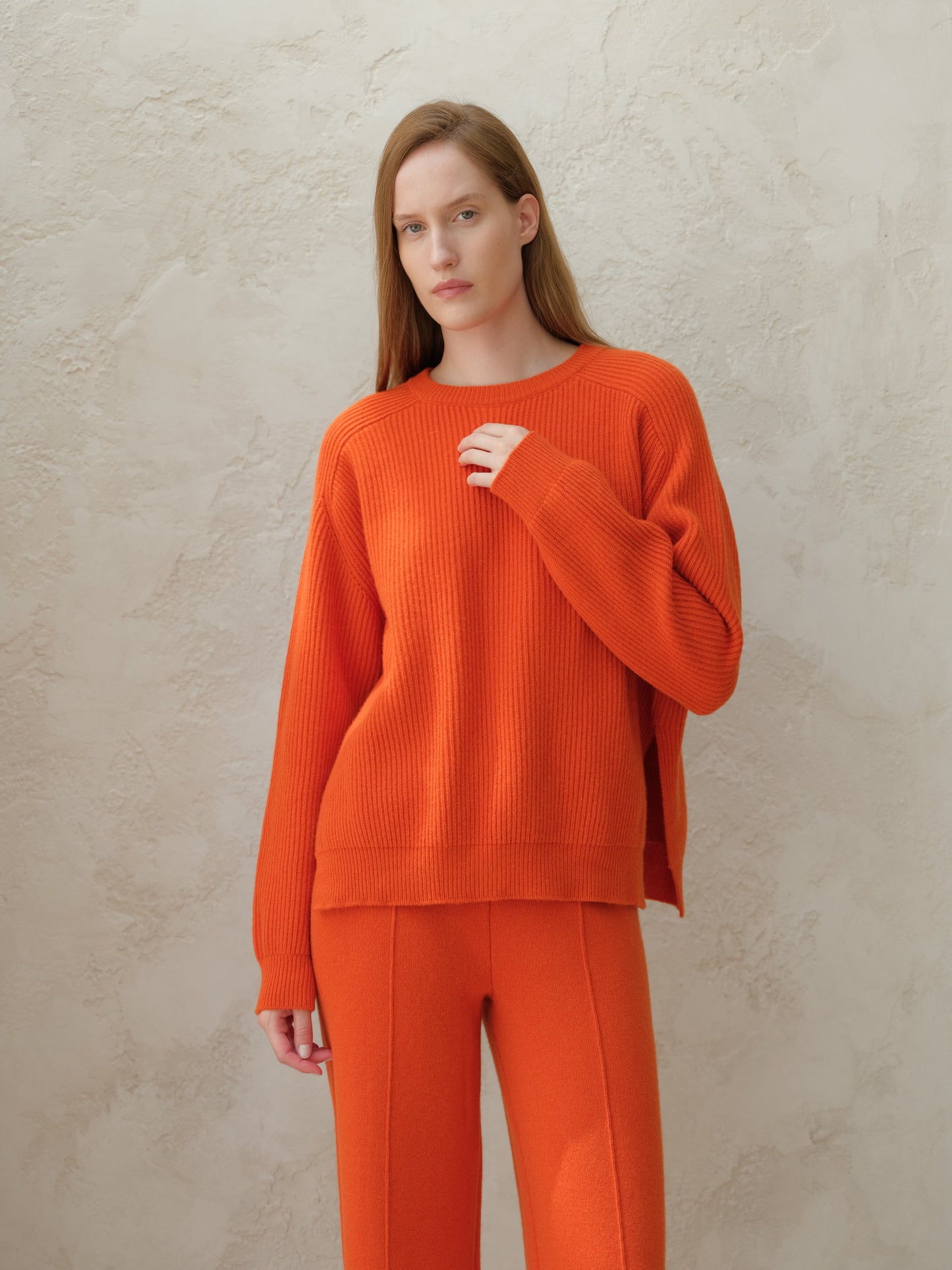 Front view of a model wearing an orange cashmere mix crewneck ribbed sweater with a relaxed fit