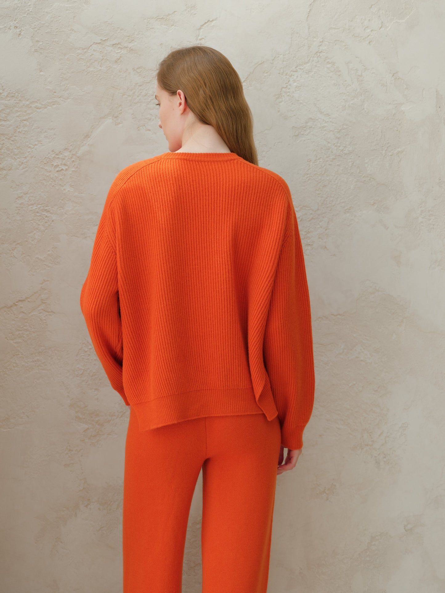 Back view of a model wearing an orange cashmere mix crewneck ribbed sweater