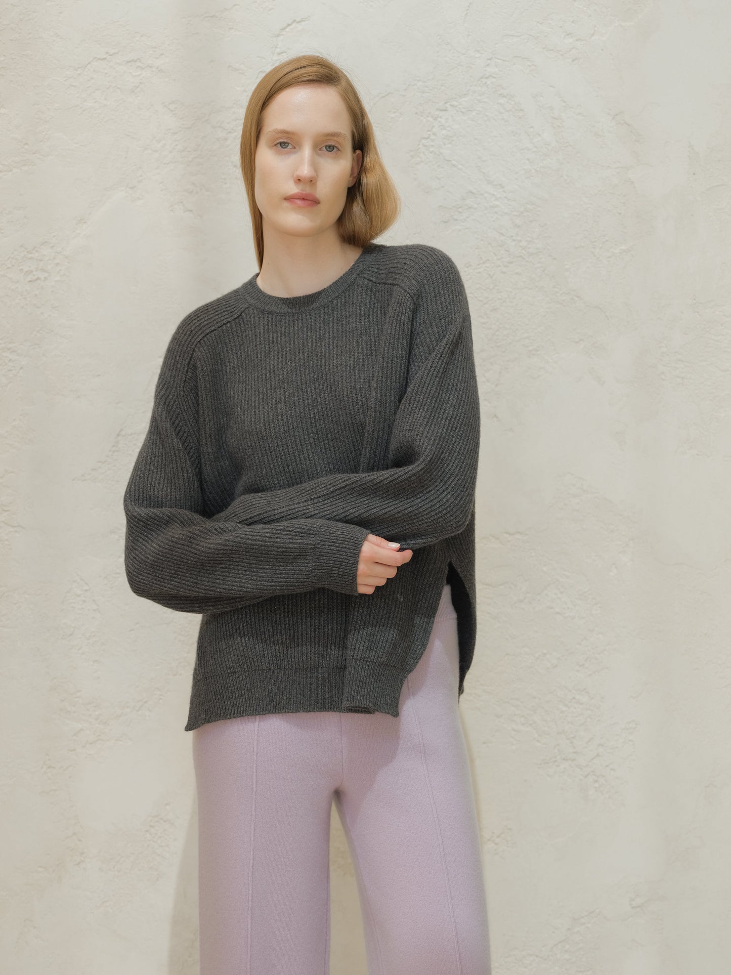 Model wearing a dark gray ribbed cashmere mix crewneck sweater with a relaxed fit and side slits