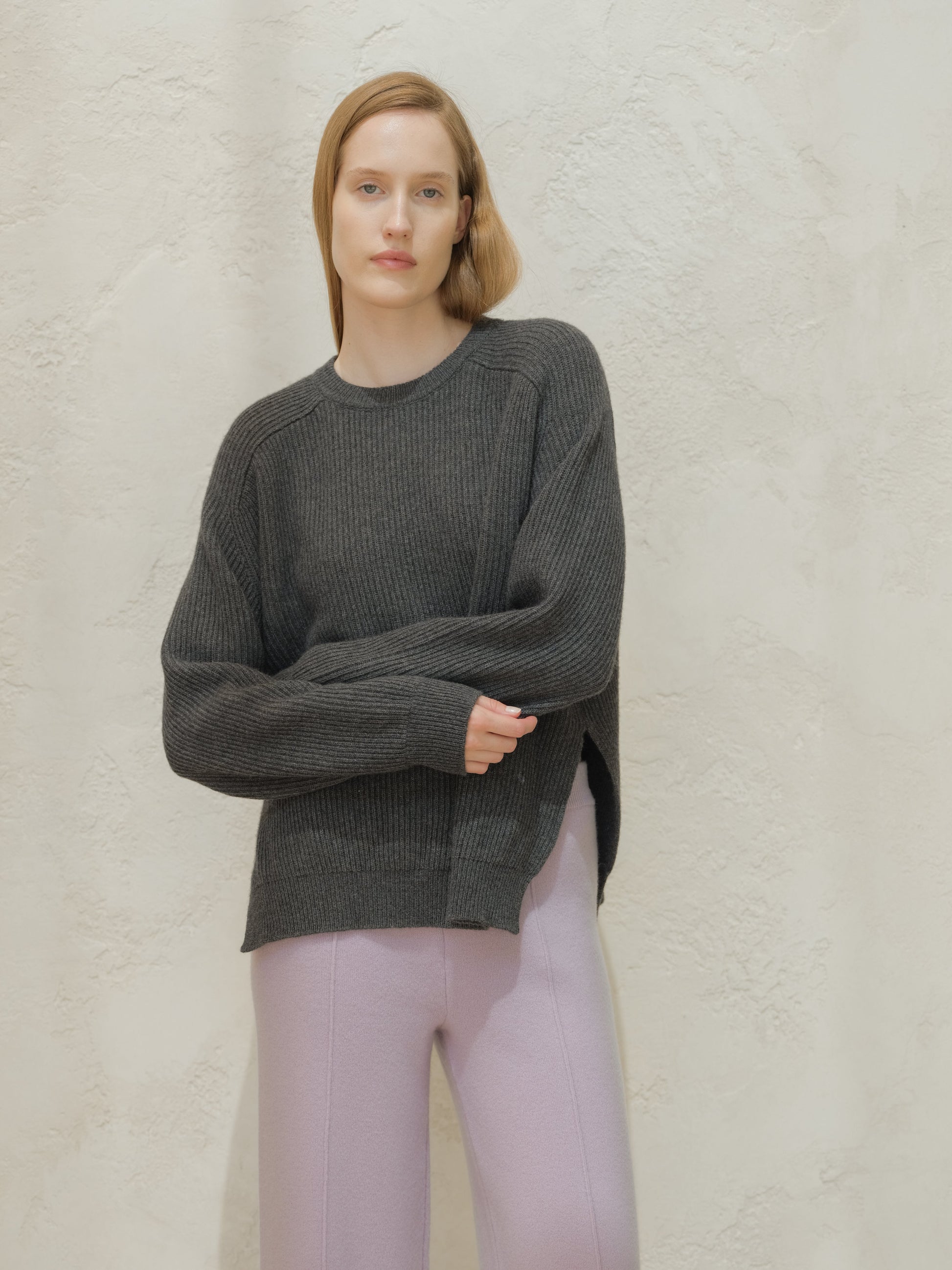 Model wearing a dark gray ribbed cashmere mix crewneck sweater with a relaxed fit and side slits