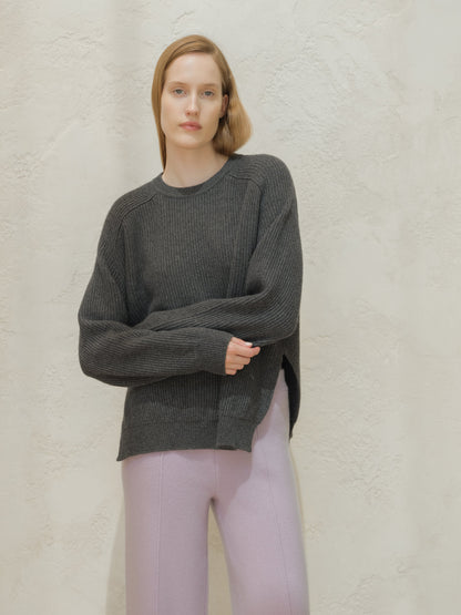 Model wearing a dark gray ribbed cashmere mix crewneck sweater with a relaxed fit and side slits
