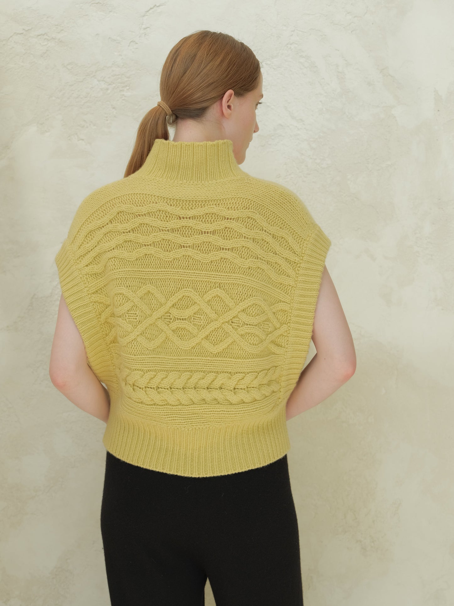 Back view of a pale yellow cable knit maxi tunic with high neck and intricate patterns.
