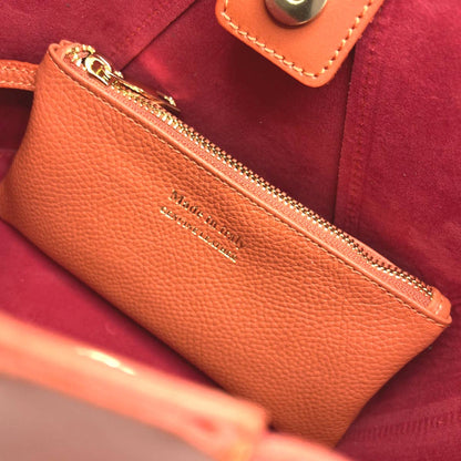 Interior of our orange Bolgheri Leather Bucket Bag showing the included pouch with gold zipper on the red lining