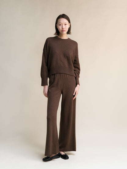 Full body shot of a model wearing a dark brown cashmere mix crewneck sweater and matching wide leg knit pants