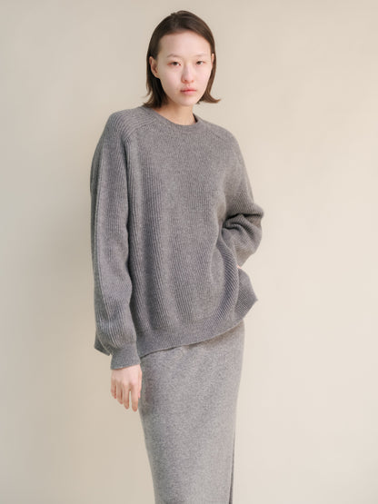 Model wearing gray ribbed cashmere mix crewneck sweater with relaxed fit and a matching knit skirt.