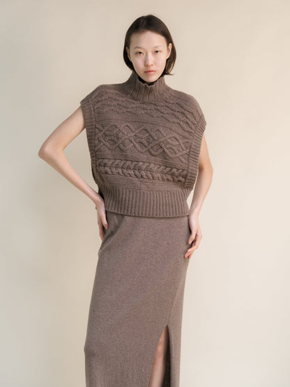 Taupe cashmere mix maxi cable tunic styled as a sleeveless high neck poncho with intricate knit patterns and side openings.
