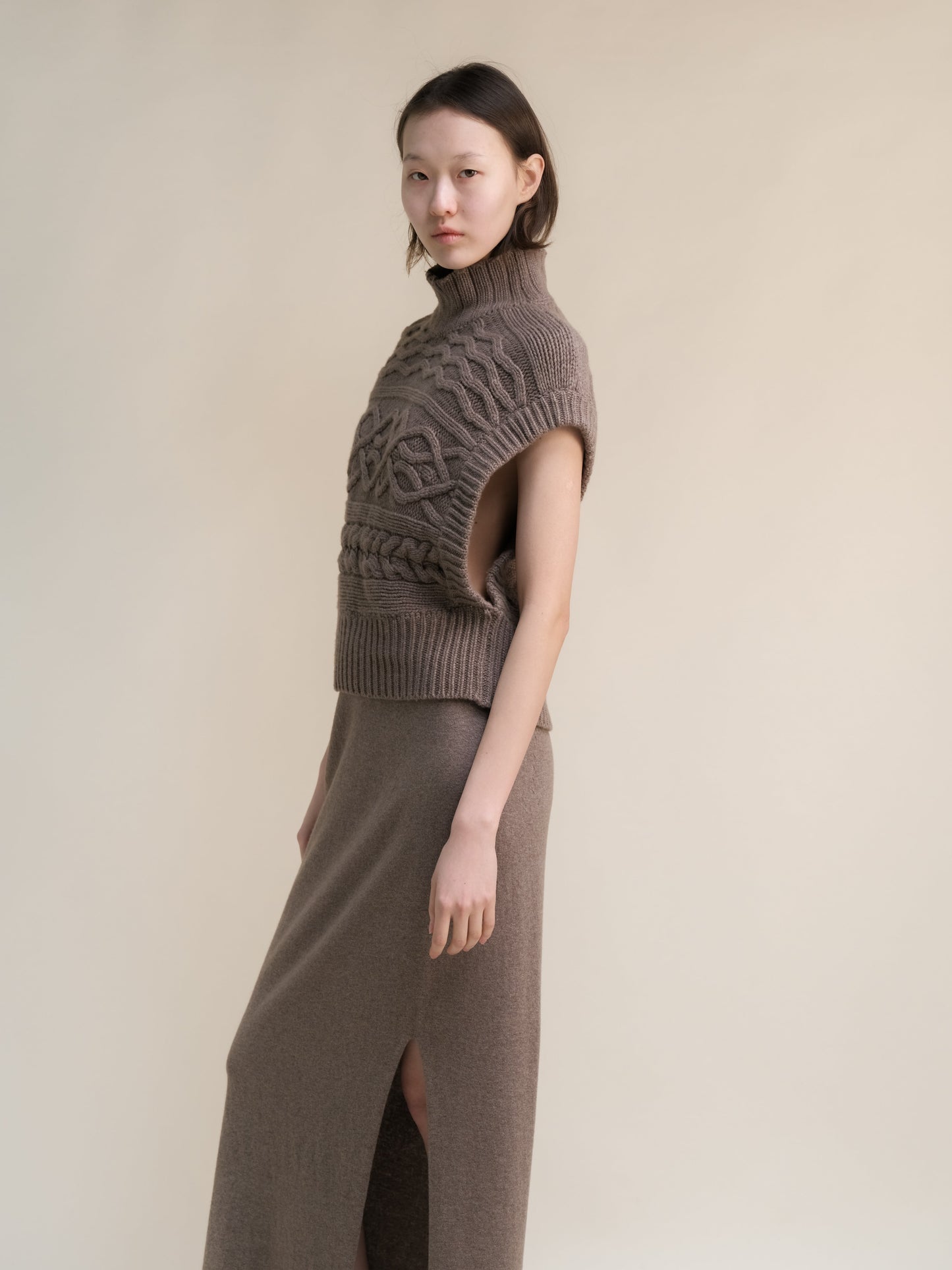 Taupe cashmere mix maxi cable tunic worn by a model with a high neck and sleeveless oversized armholes