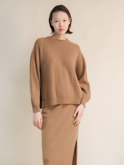 Model wearing camel ribbed cashmere mix crewneck sweater with relaxed silhouette and a matching long skirt.
