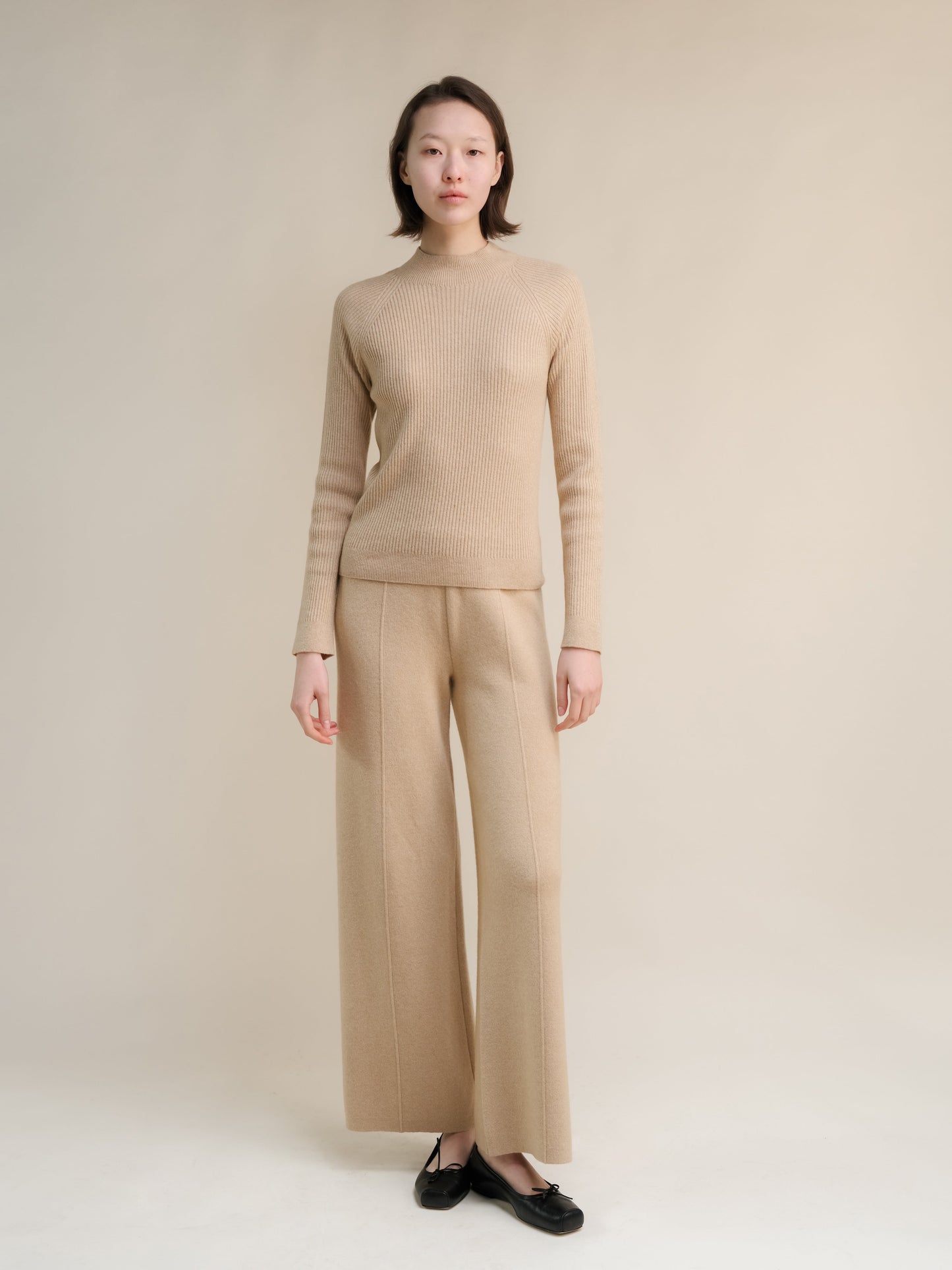 Cream 3D-Knit cashmere mix ribbed mock neck sweater on a model with matching wide-leg trousers.