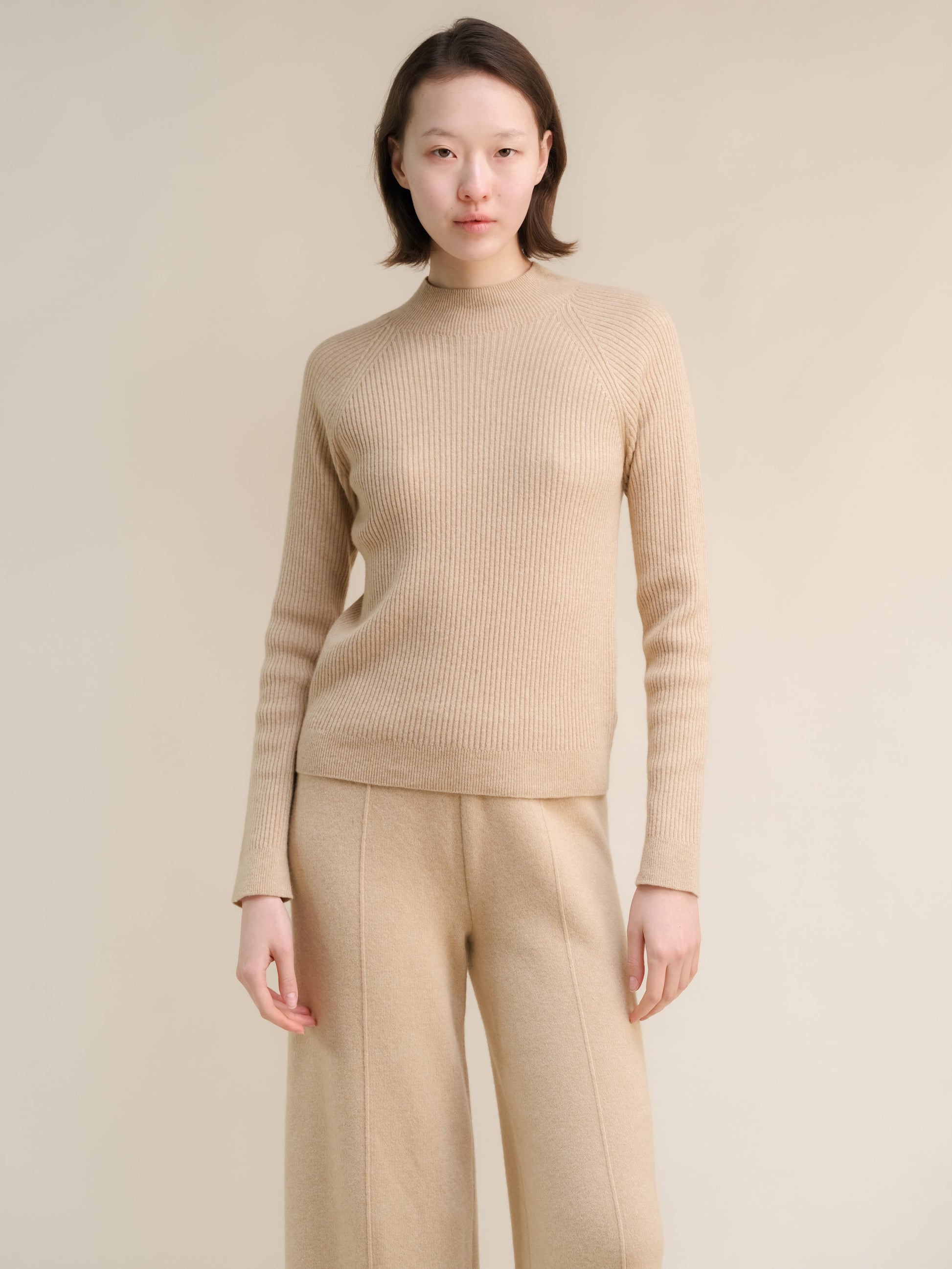 Beige 3D-Knit cashmere mix ribbed mock neck sweater on a model with coordinating beige trousers.