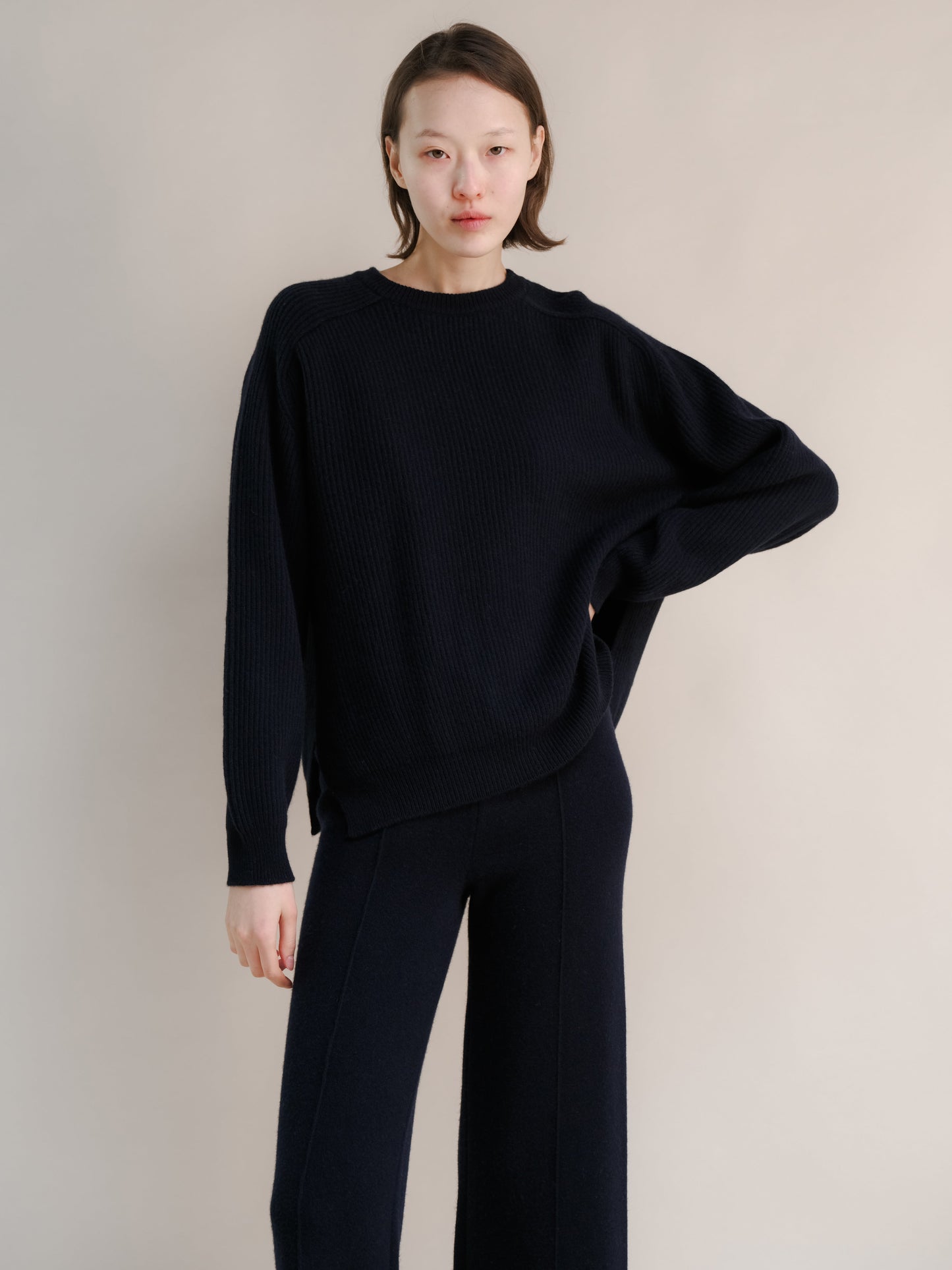 Model wearing navy cashmere mix crewneck ribbed sweater with lateral slits