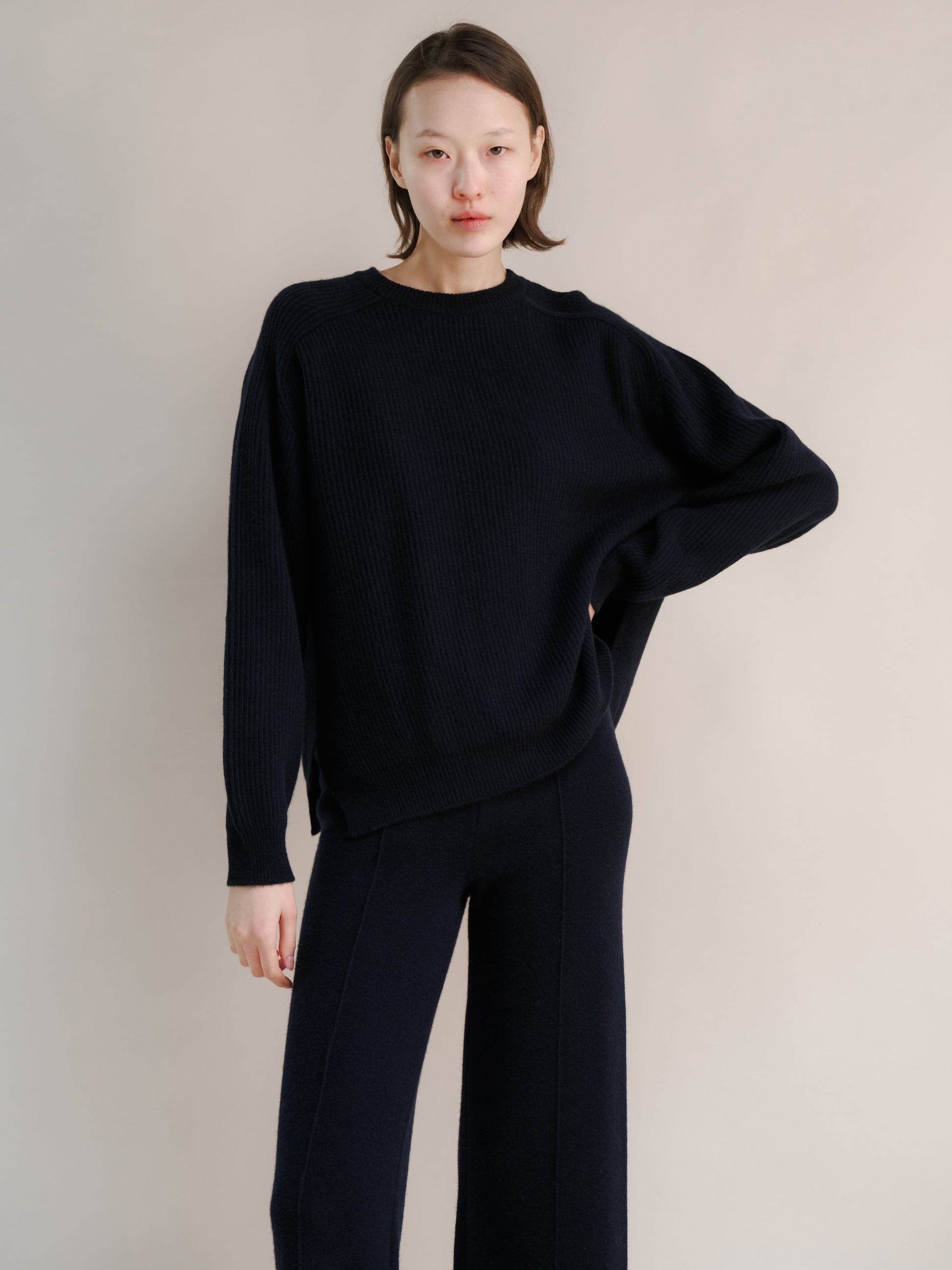 Model wearing navy cashmere mix crewneck ribbed sweater with lateral slits