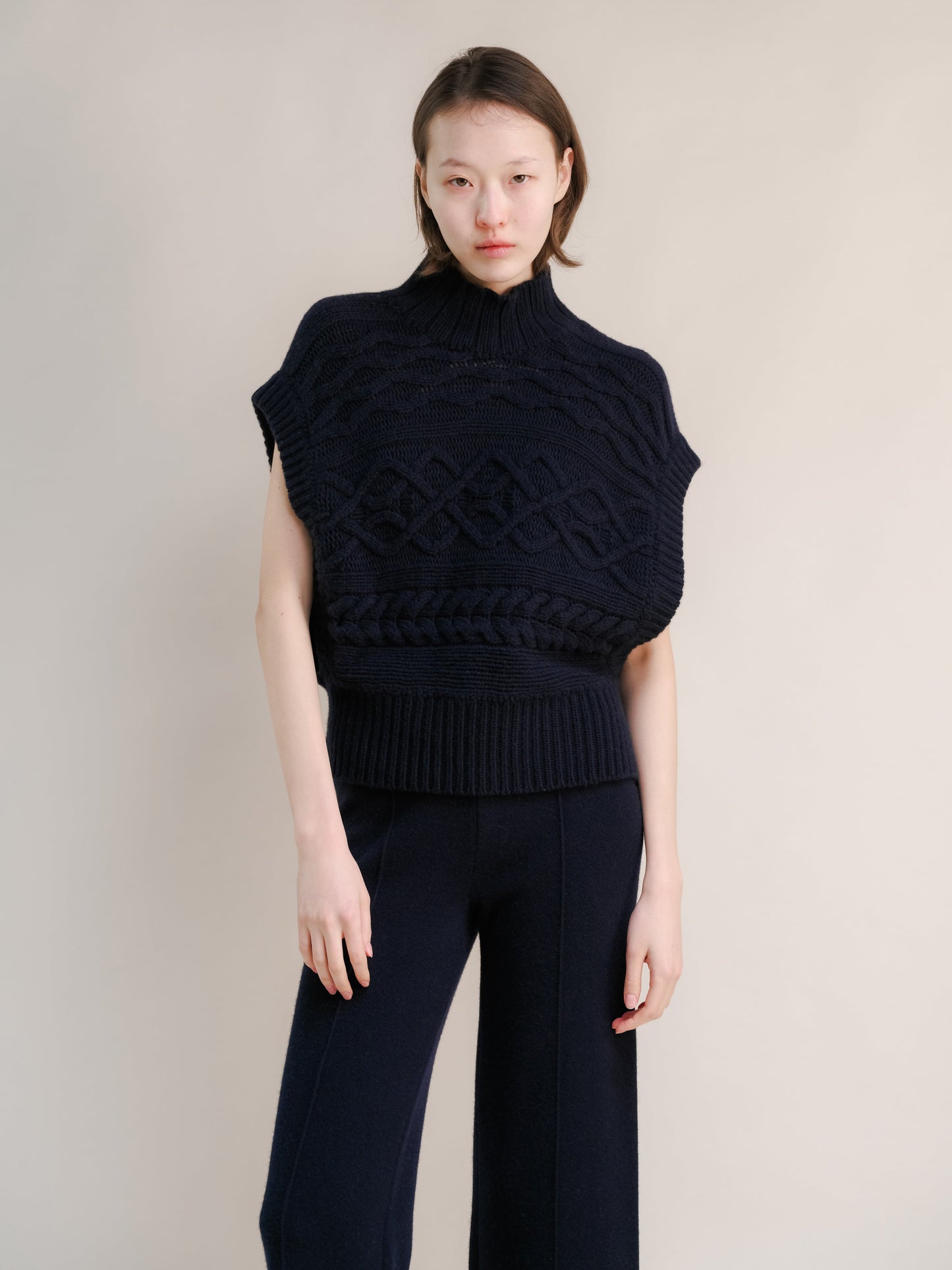 Navy cashmere mix maxi cable tunic on a model featuring a chunky knit pattern and ribbed hem with a high neck.