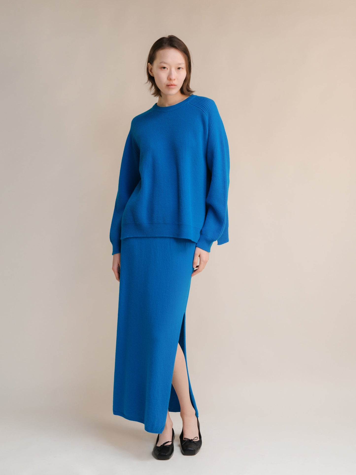 Model wearing a bright blue cashmere mix crewneck ribbed sweater with a matching blue maxi skirt in a studio