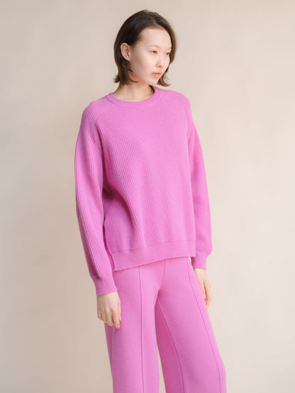 Model wearing a pink cashmere mix crewneck ribbed sweater with side slits and matching pink pants
