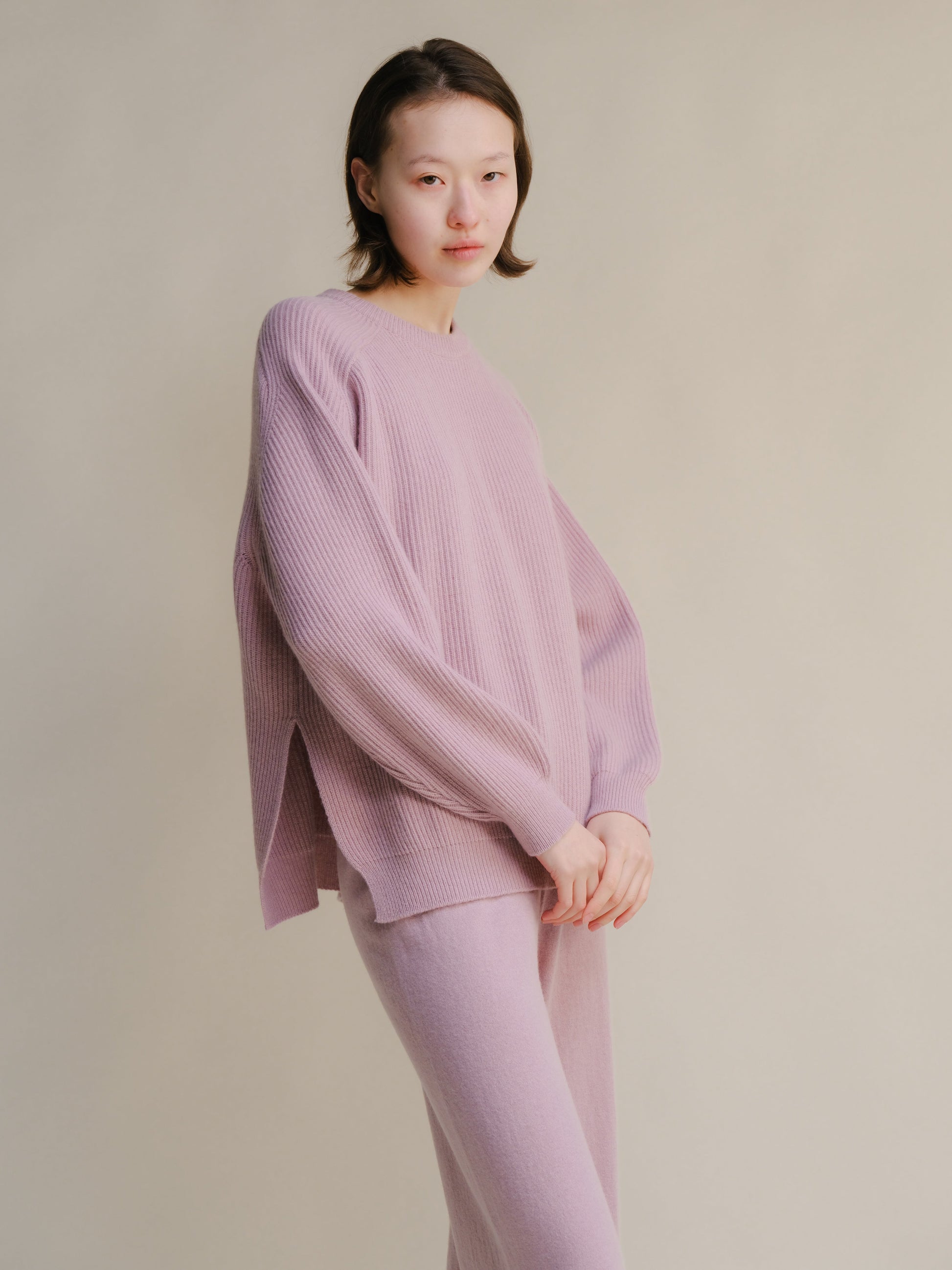 Model wearing soft lavender ribbed cashmere mix crewneck sweater with side slits and matching pants