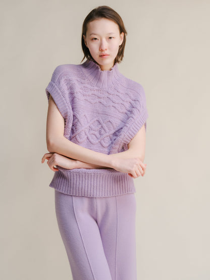 Lilac chunky knit sleeveless tunic with a high neck and cable pattern worn with matching lilac pants.