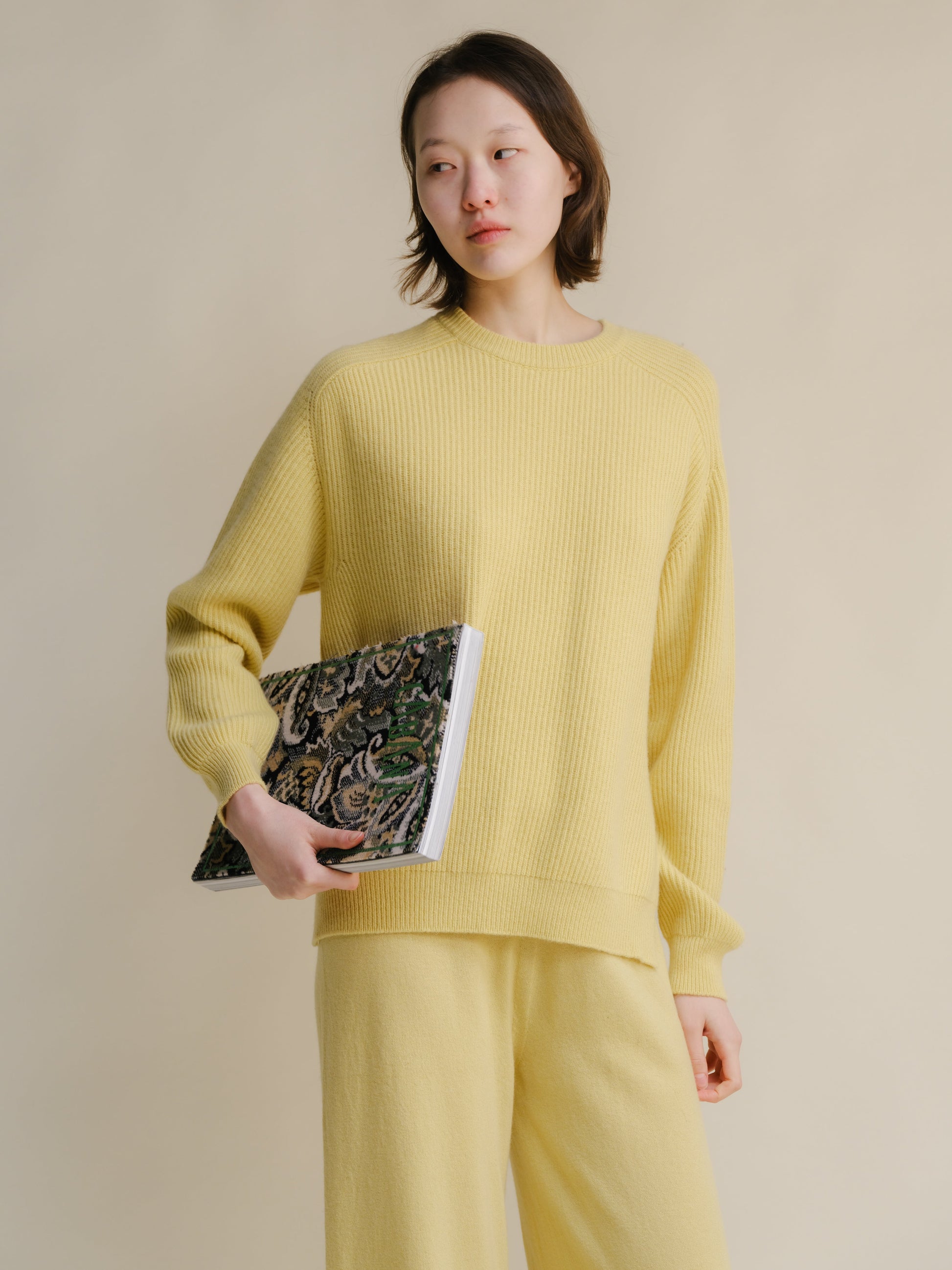 Model in pale yellow cashmere mix crewneck ribbed sweater with side slits, paired with matching knit pants