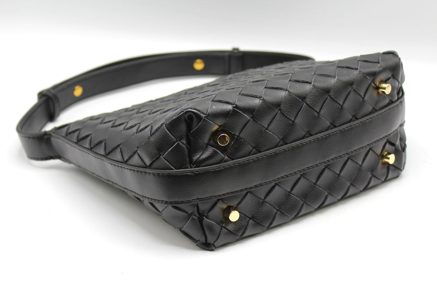 Angled view of black woven leather box pouch showing gold studs and stitched edges