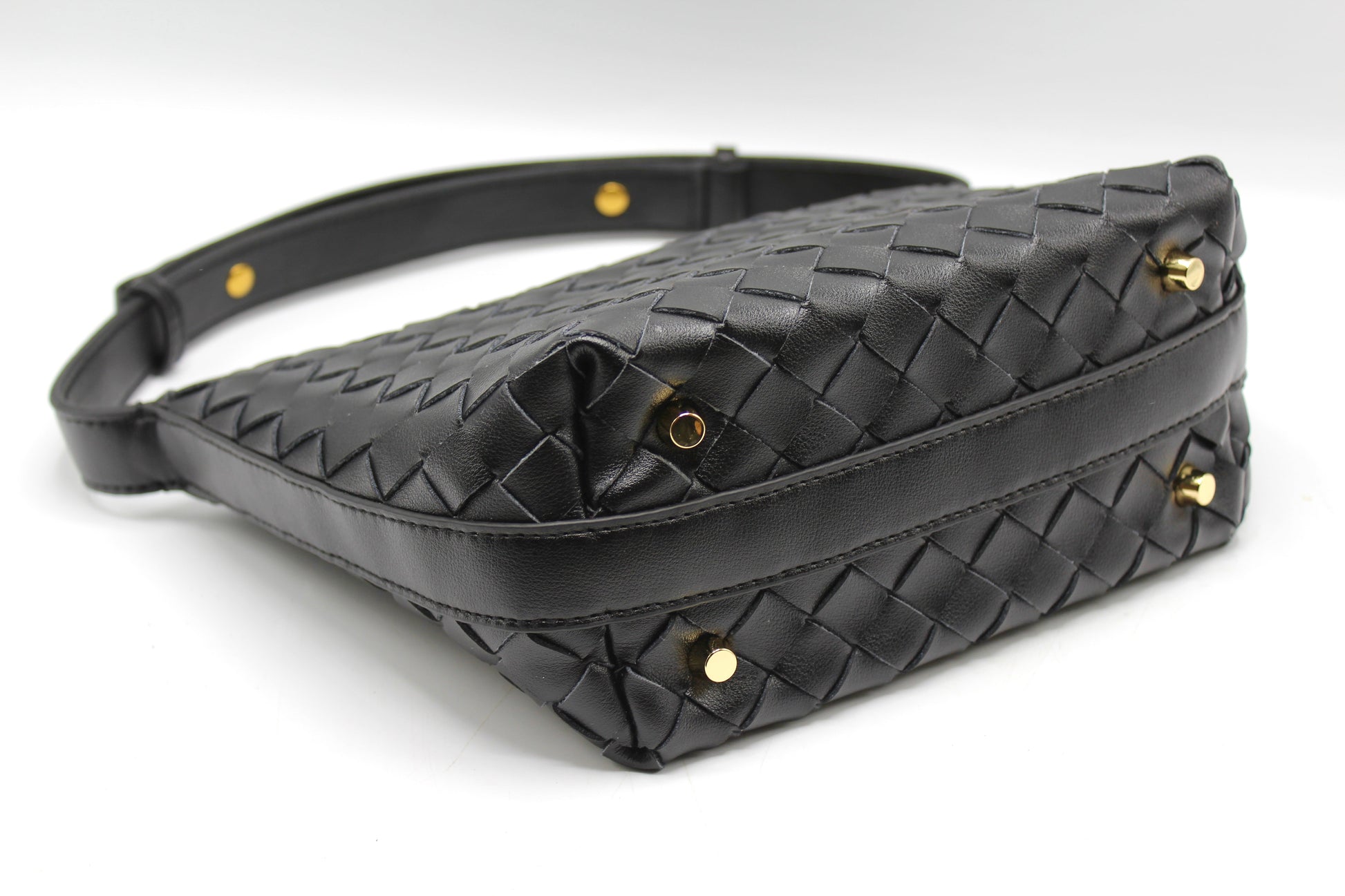 Angled view of black woven leather box pouch showing gold studs and stitched edges