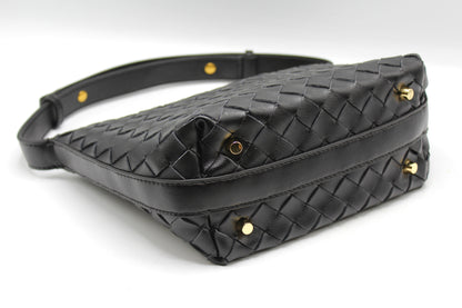 Angled view of black woven leather box pouch showing gold studs and stitched edges
